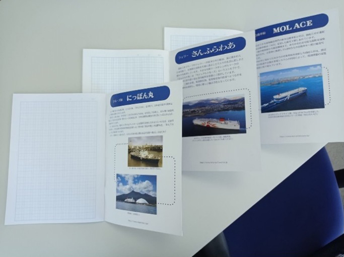 漢字練習帳の中身が開かれており、漢字の書き取り用の方眼罫ページが見える。反対側のページには、MOLの船舶に関する写真と説明が掲載されており、学習のための追加教材となっている。
