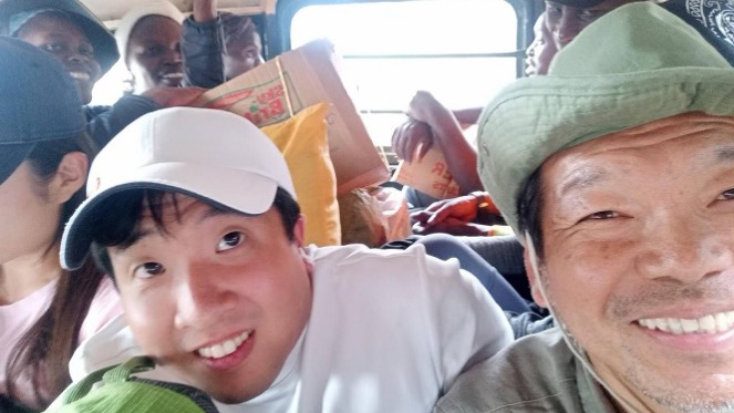 現地のバスにぎゅうぎゅう詰めで乗っている人々。笑顔で冒険を楽しんでいる様子。