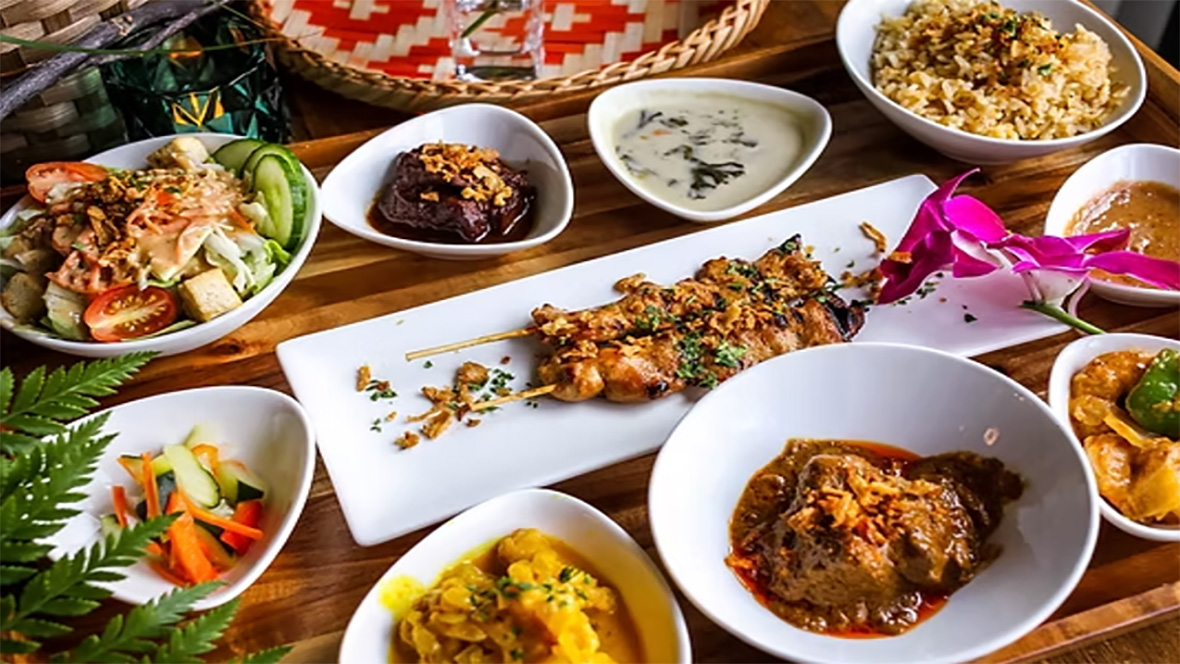 A traditional Mozambican meal featuring various colorful dishes including grilled meat skewers, vegetables, sauces, and rice.