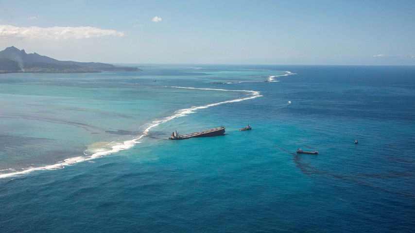 Aerial view of the MV Wakashio grounded off the southeast coast of Mauritius, surrounded by turquoise waters and reef lines, with response vessels nearby.