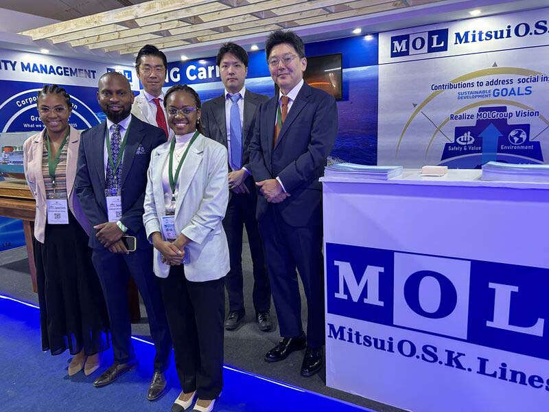 FACIM 2024の展示ブースで撮影されたMOLマプト事務所チームとMOL（欧州・アフリカ）代表者の集合写真。背景にはMOLのロゴやサステナビリティに関する展示が見える。