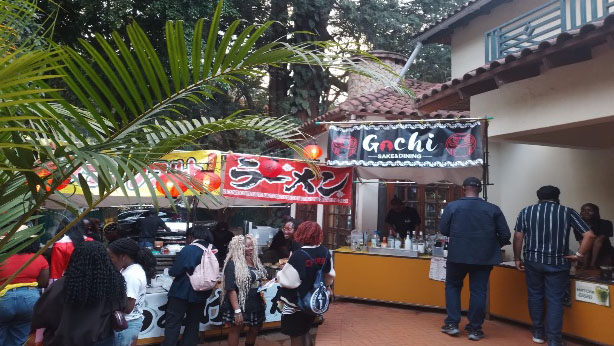 Festival visitors gathering near Japanese food stalls decorated with ramen banners and lanterns at Gochimatsuri in Kenya.