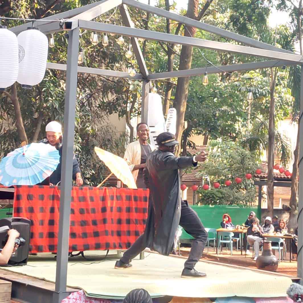 Samurai-style performance on an outdoor stage decorated with lanterns and umbrellas during a Japanese festival in Kenya.