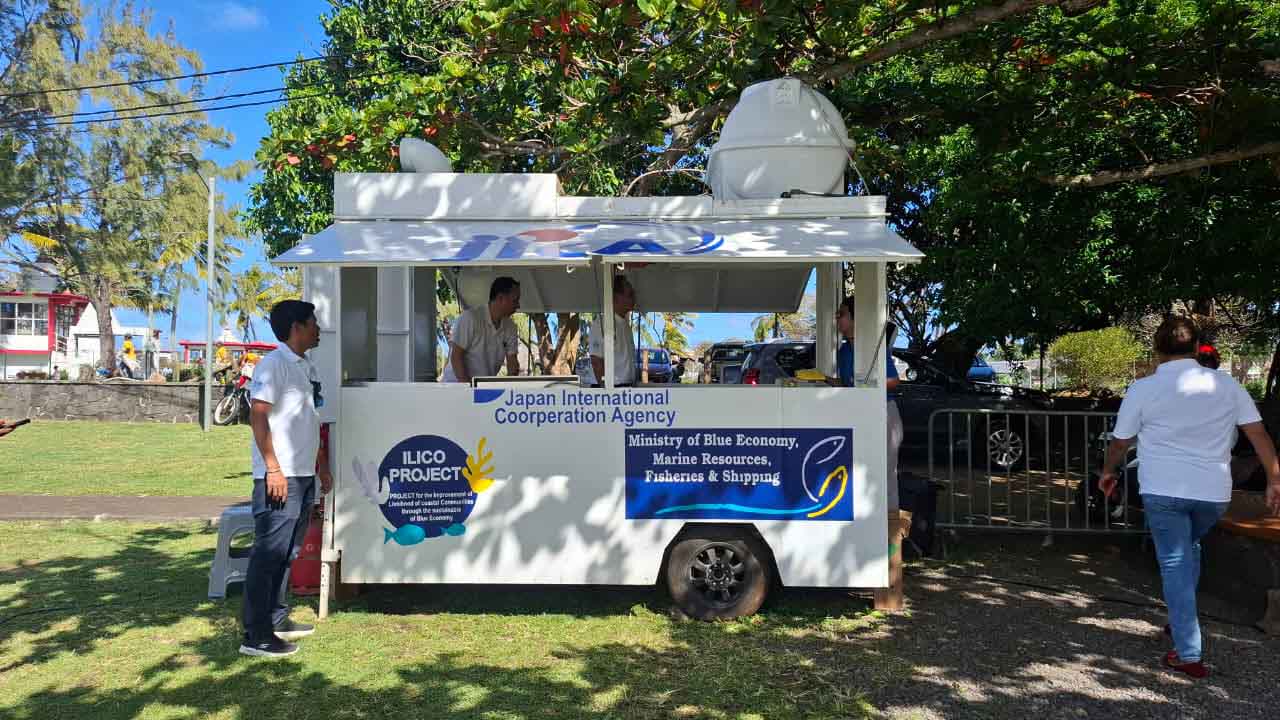 Japanese chef preparing food inside the JICA Kitchen Car alongside MOL Mauritius members.