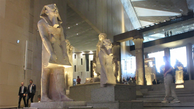 大エジプト博物館の広大な展示ホールに並ぶ古代エジプトの巨大な石像。古代エジプト文明の優れた彫刻技術と芸術的な功績を伝える。